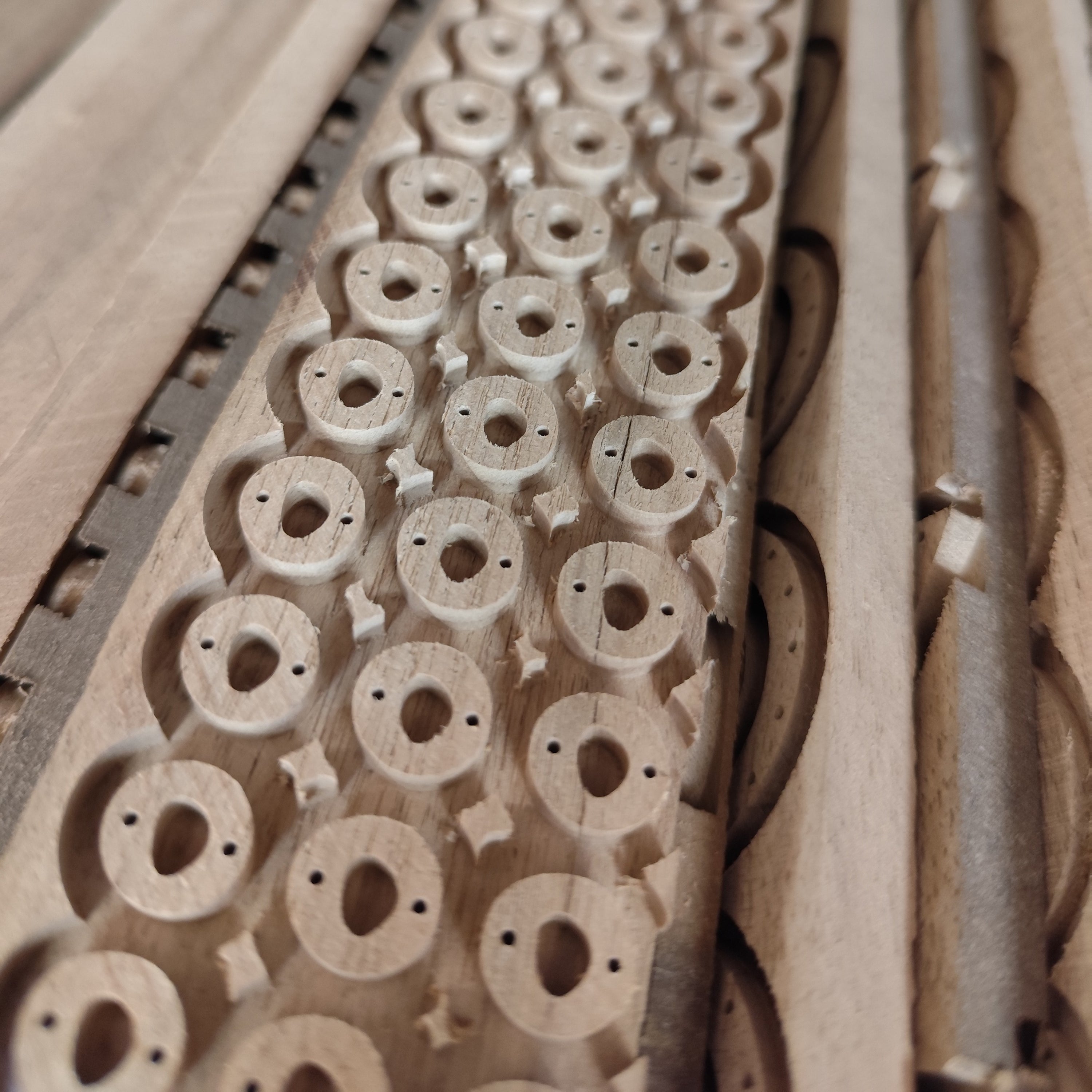 Ausgefräste CNC-Formen aus Nussholz, ungeschliffen und ungeölt, als Rohmaterial für handgefertigte Holzschmuckteile in der Werkstatt