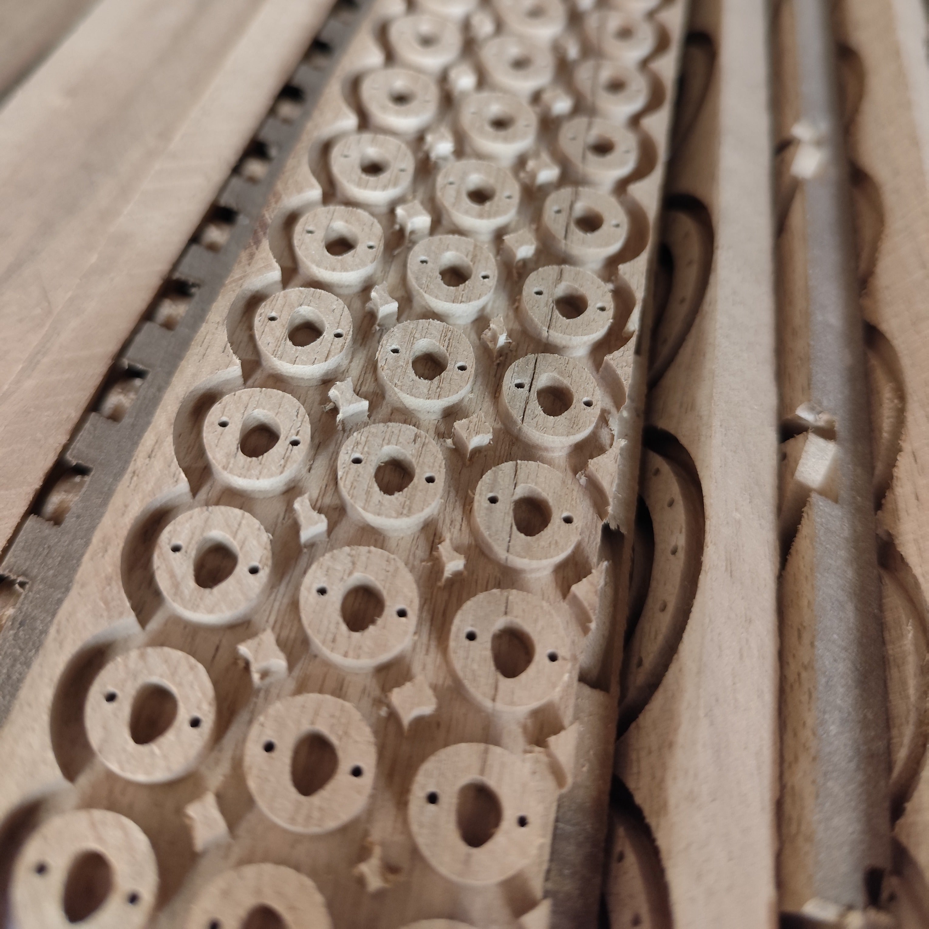 Ausgefräste CNC-Formen aus Nussholz, ungeschliffen und ungeölt, als Rohmaterial für handgefertigte Holzschmuckteile in der Werkstatt