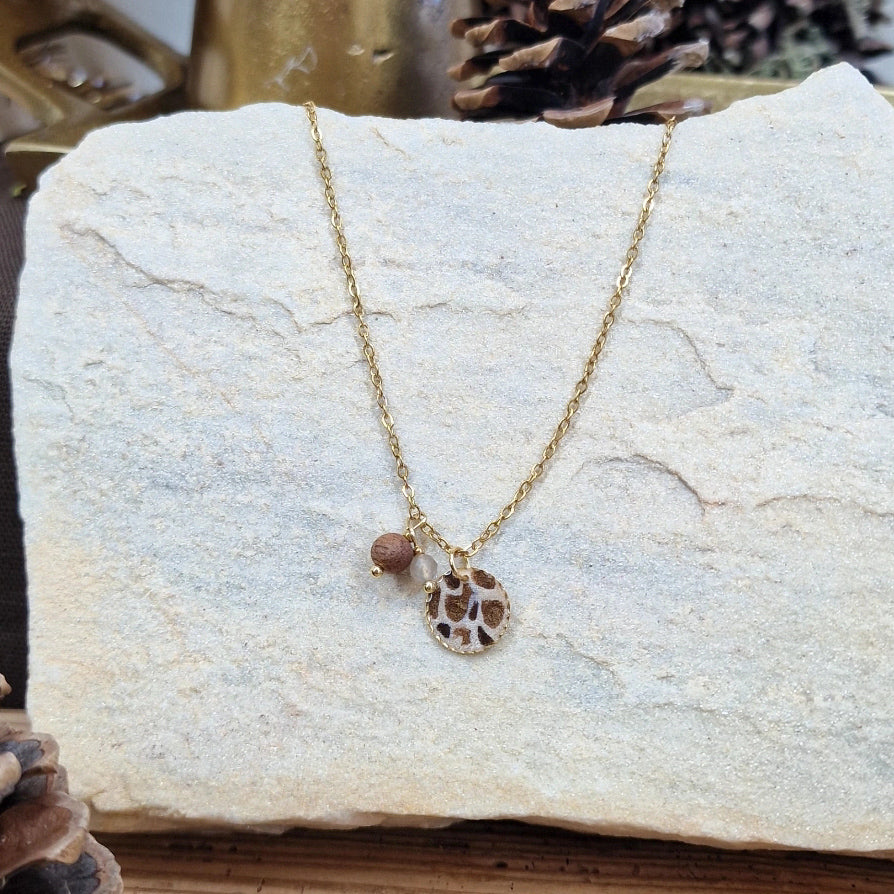 Handgefertigte Halskette ‚Leopardis‘ mit rundem Resin-Anhänger im Leo-Design, Nussholz und Mondstein an feiner Kette aus Edelstahl, fotografiert auf Naturstein
