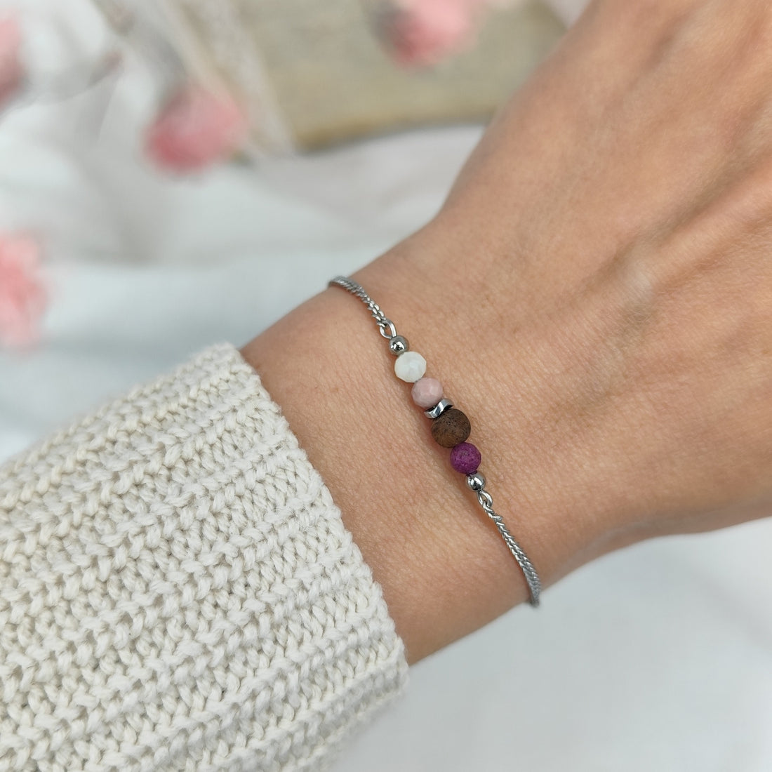 Fein gearbeitetes Armketterl mit rosé- und violettfarbenen Natursteinen an silberfarbener Kette, am Handgelenk getragen