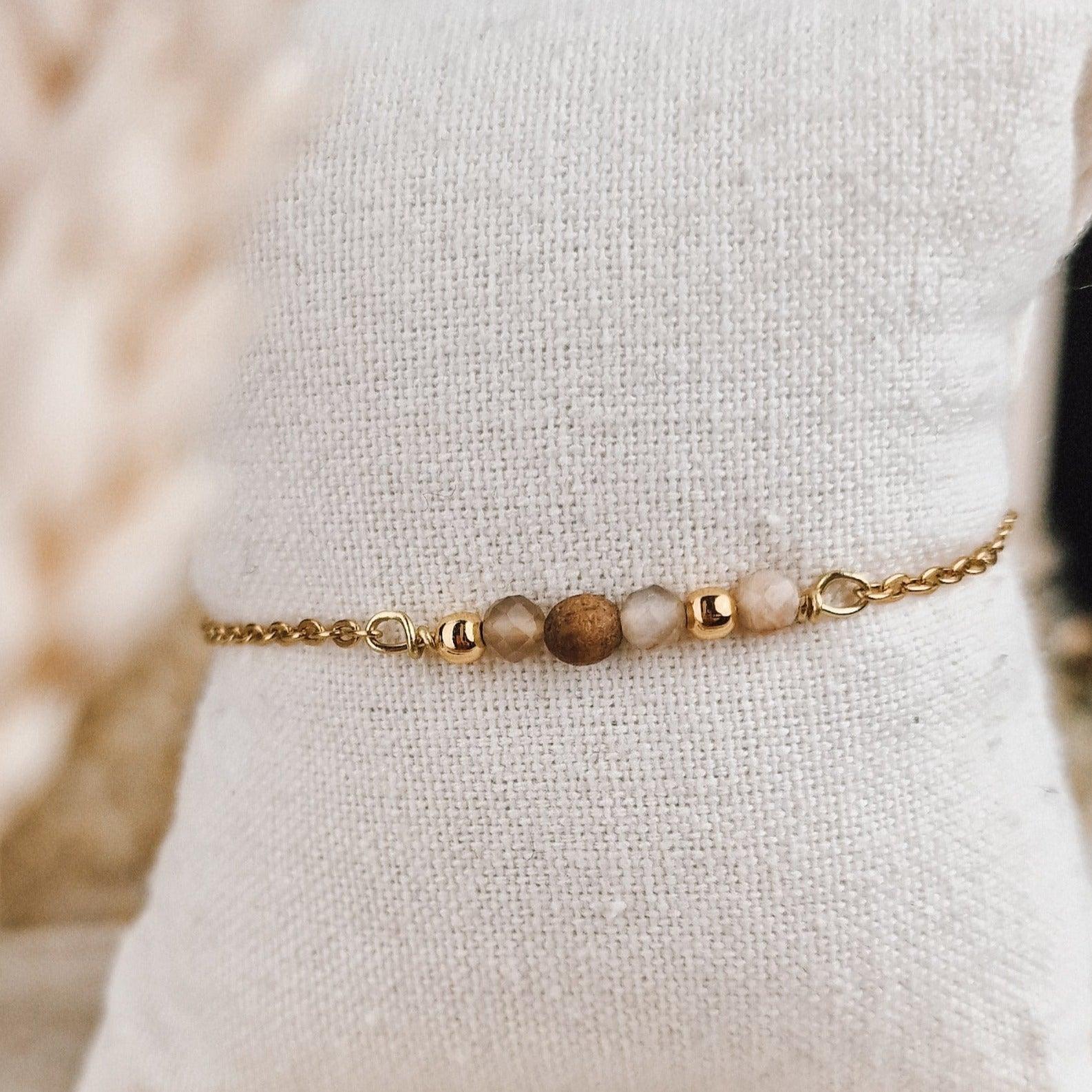 Schlichtes handgefertigtes Armband mit Nussholz-Perlen und beigem Textilband auf hellem Stoffhintergrund.