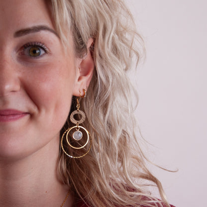 Detailansicht von goldfarbenen Ohrringen aus Nussholz und weißem Quarz am Ohr getragen