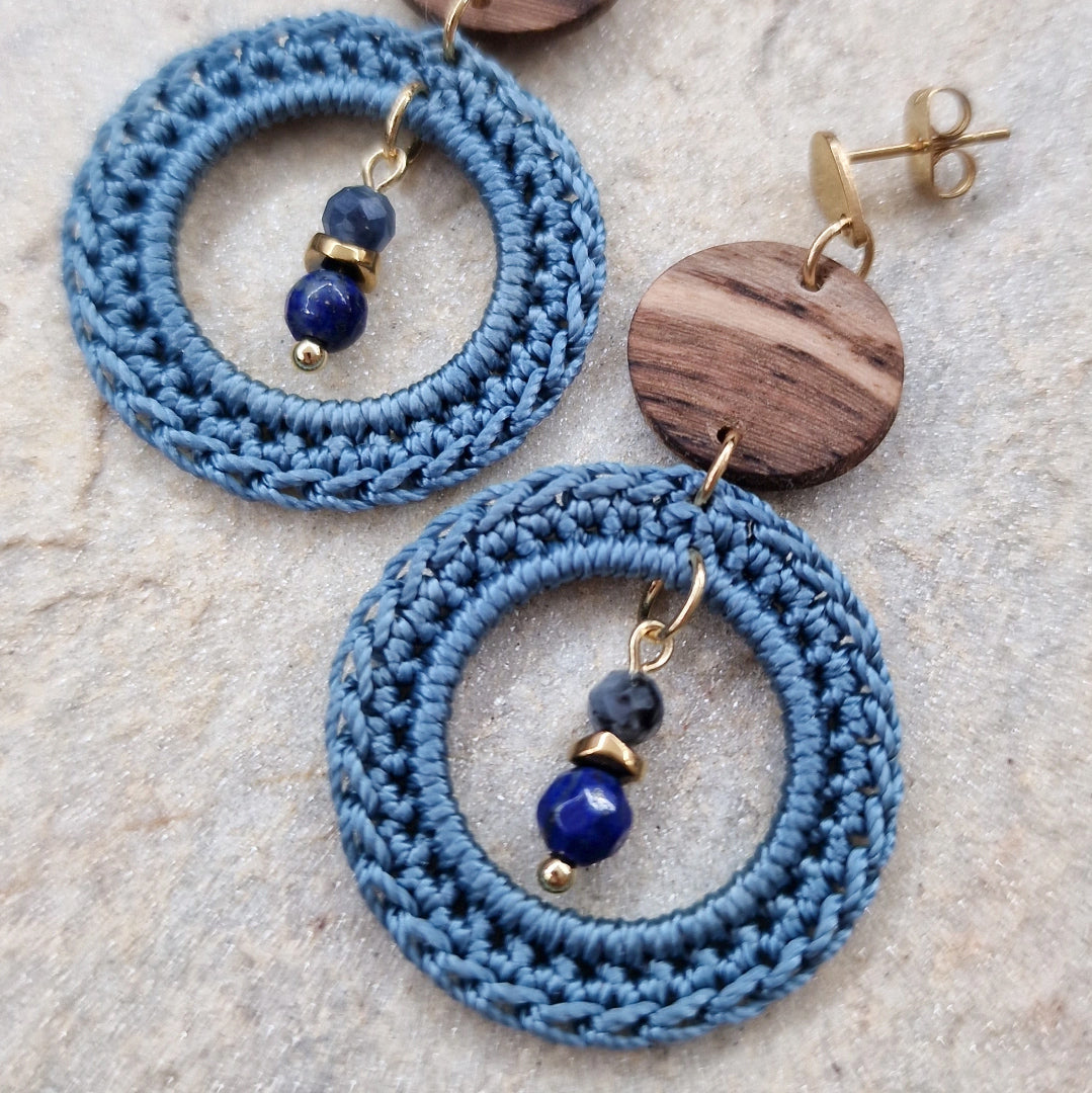 Detailaufnahme der gehäkelten blauen Ringe mit Natursteinperle und Weinstockholz-Element