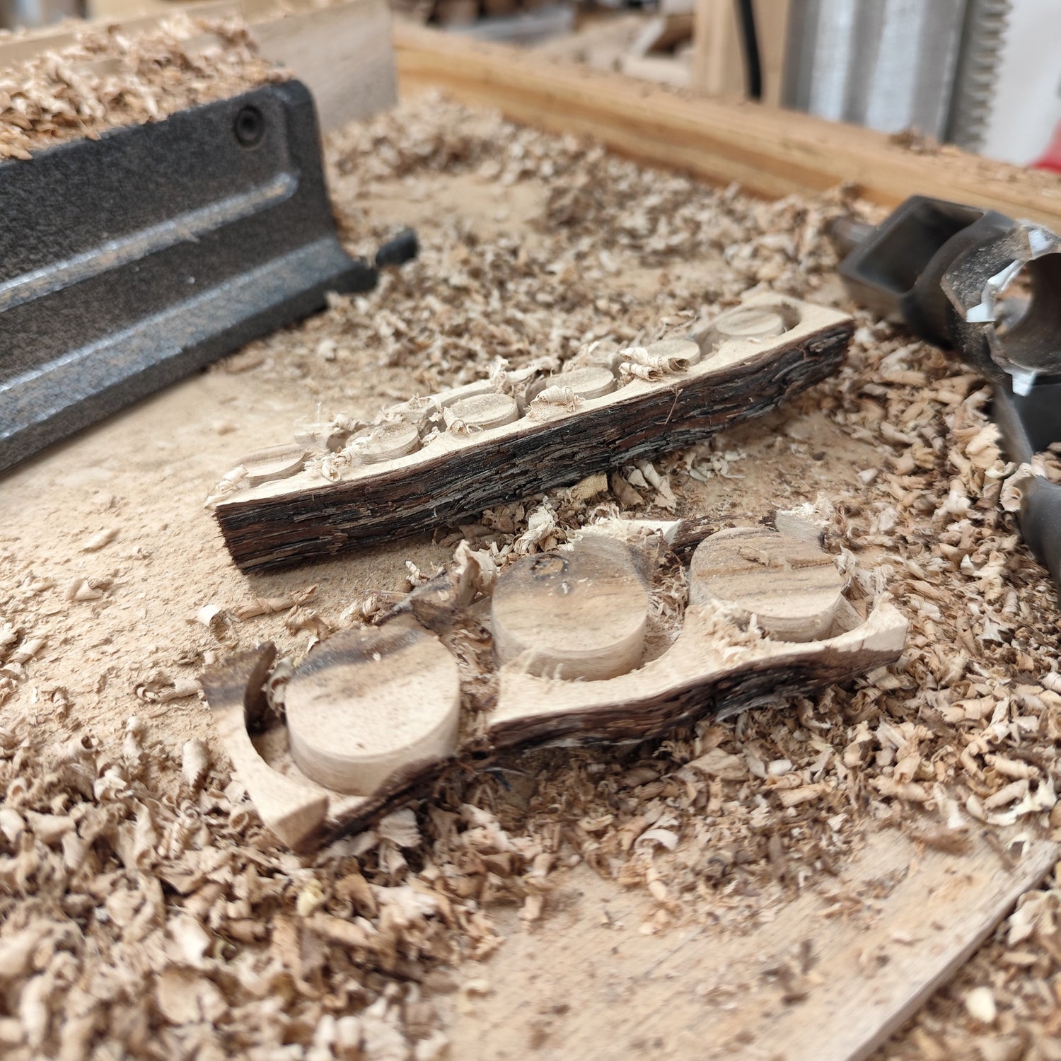 Werkstattaufnahme mit Holzspänen und bearbeiteten Holzscheiben aus Weinstockholz während der Schmuckherstellung