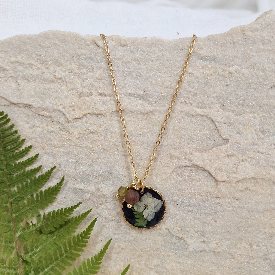 Handgefertigte Halskette ‚Waldlicht‘ mit rundem Anhänger aus schwarzem Resin mit echten Blüten und Farnen, Nussholz und Natursteinen an feiner Edelstahlkette