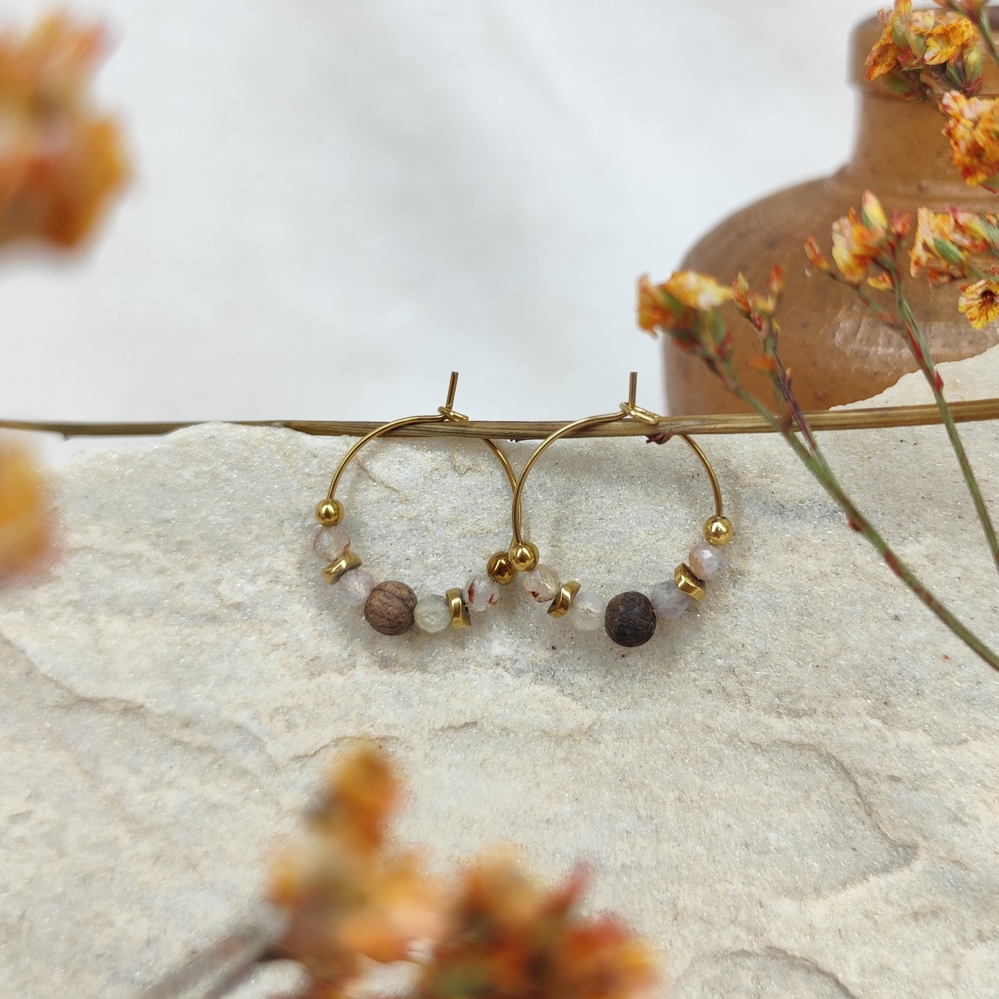 Detailansicht der kleinen Kreolen mit zwei unterschiedlich gefärbten Perlen – eine hell schimmernd, eine braun – fotografiert auf einem natürlichen, hellen Hintergrund