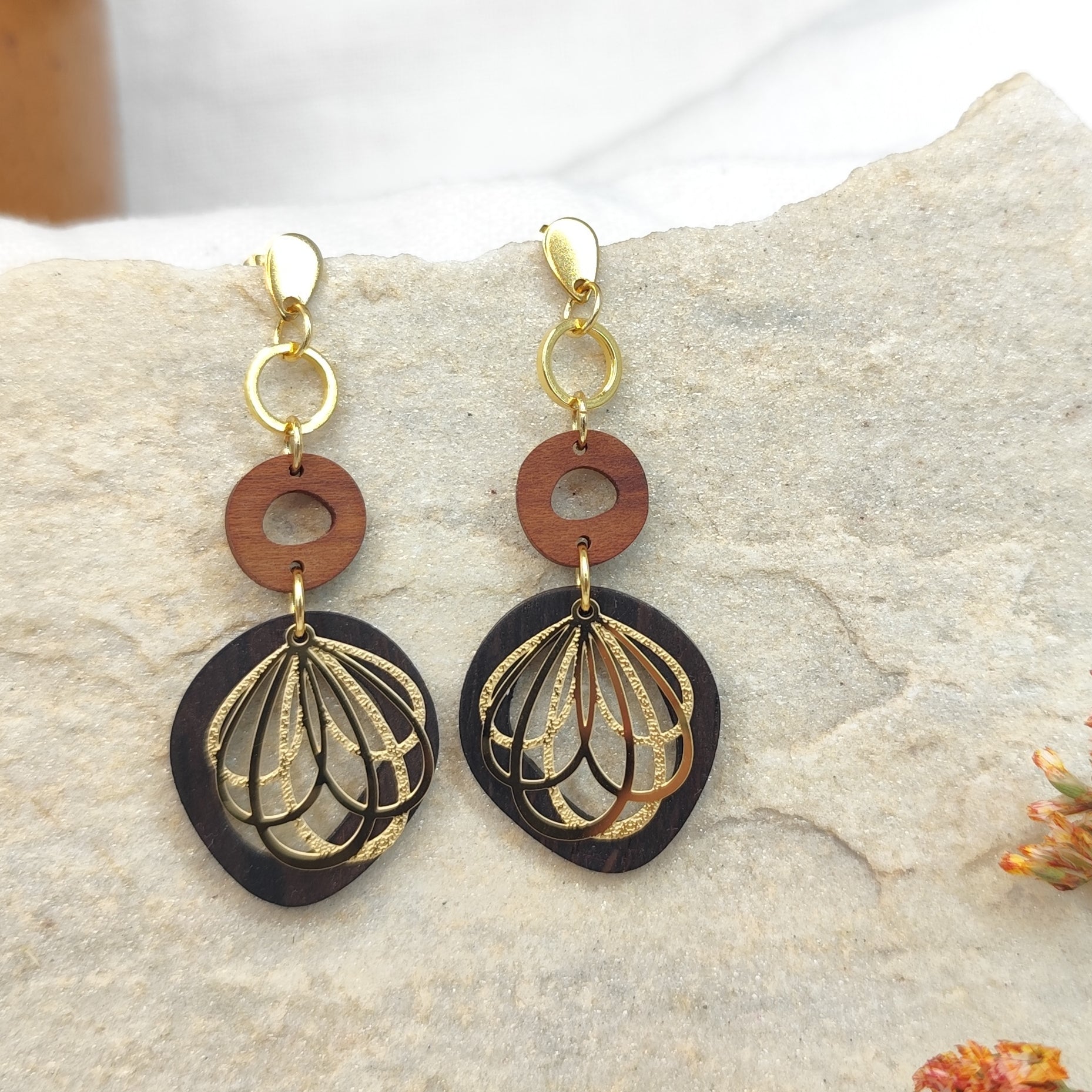 Handgefertigter Holzohrring auf hellem Stein