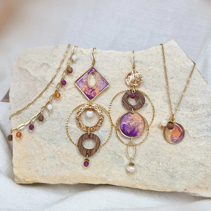 Variation des handgefertigten Holzschmuck-Sets aus Nussholz mit Resinelementen, Natursteinen, Ohrringen, Halskette und Armband, arrangiert auf hellem Naturstein