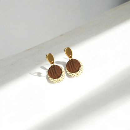 Paar handgefertigte Ohrringe aus Nussholz mit vergoldeten Edelstahl-Elementen, frontal fotografiert auf hellem Hintergrund.