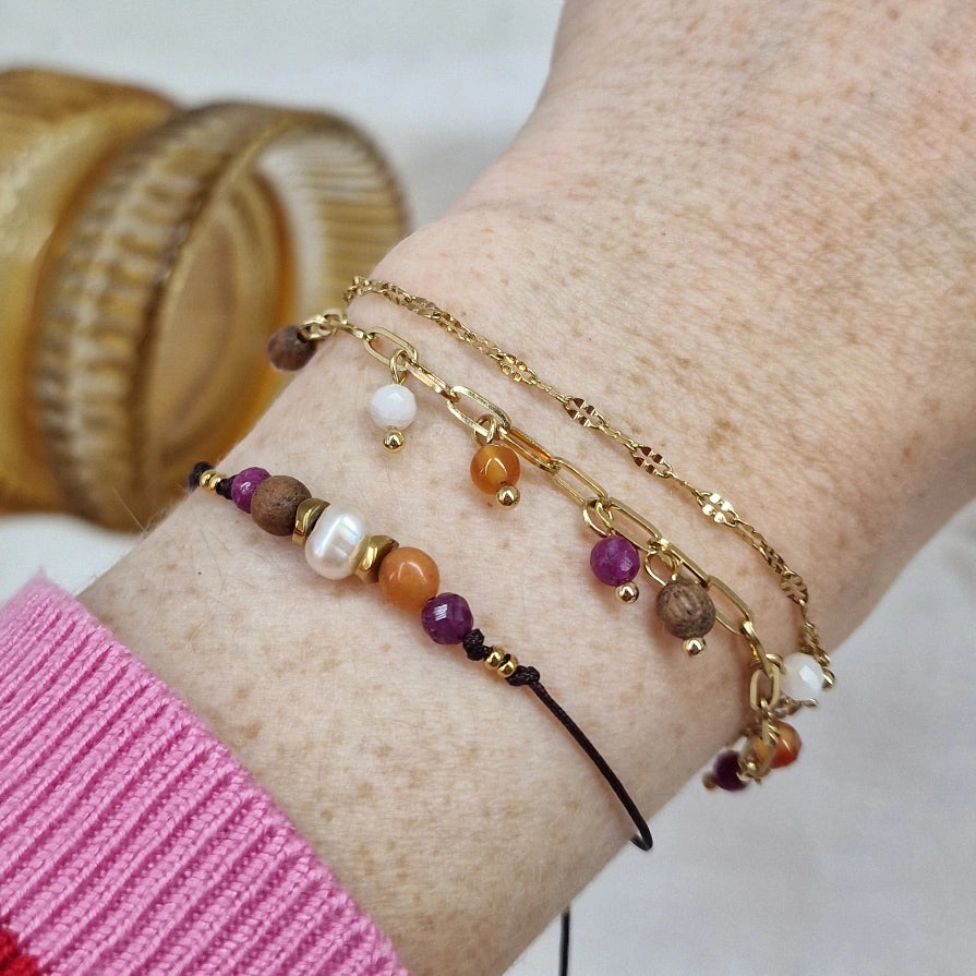 Handgefertigtes Holzarmband aus Nussholz mit Natursteinen und Hämatit, getragen am Handgelenk und mit anderem Armband kombiniert