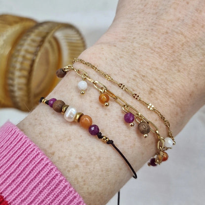 Handgefertigtes Holzarmband aus Nussholz mit Natursteinen und Hämatit, getragen am Handgelenk und mit anderem Armband kombiniert