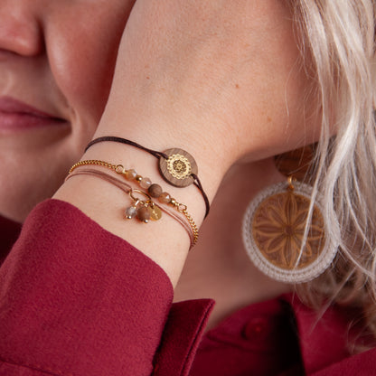 Handgefertigte Armbänder aus Nussholz und Mondstein am Handgelenk getragen, natürliche Hauttöne und weiches Licht.