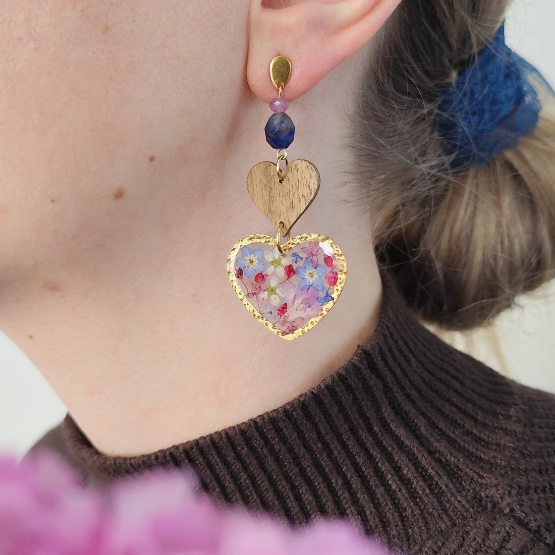Ohrring aus Holzherz und Resinherz mit echten Blüten und Natursteinen am Ohr getragen. 