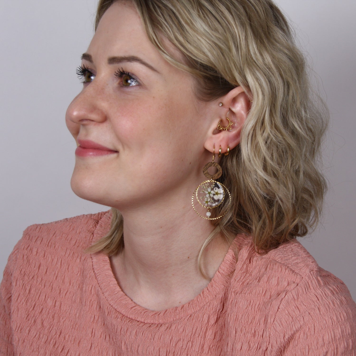 Blonde Frau im Halbprofil mit handgefertigten Ohrringen &