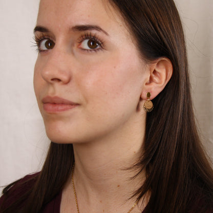 Frau mit handgefertigten Ohrringen aus Nussholz und vergoldetem Edelstahl, getragen am Ohr