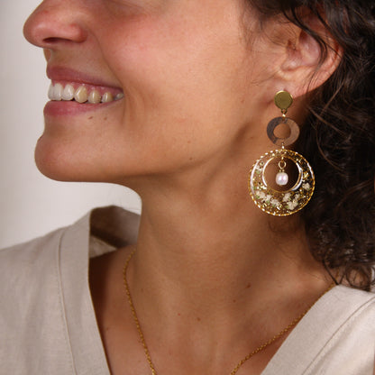 Große runde Ohrringe mit Nussholz-Element und transparentem Resin mit getrockneten Blüten und Blattgold im Profil getragen.