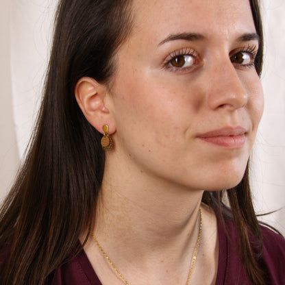 Frau im Halbprofil mit runden Nussholz-Ohrringen und goldfarbenem Blumenornament im Ohr